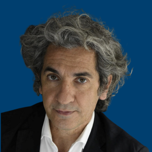 Diego Bernardini con expresión seria, vestido con camisa blanca y traje oscuro, frente a un fondo azul.