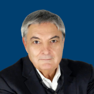 Juan Martín con expresión seria, vestido con traje oscuro, frente a un fondo azul.